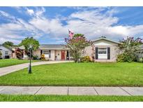 Charming single-story home featuring a well-manicured lawn, complemented by blooming plants and mature trees under a bright, cloudy sky at 3010 Brandywine Dr, Orlando, FL 32806