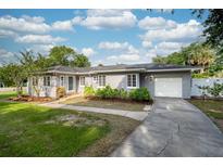 Charming gray single-story home with a well-manicured lawn, front garden, and attached garage at 311 Cortland Ave, Winter Park, FL 32789