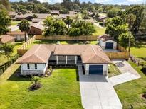 Expansive aerial view of a single-story home with a detached garage, fenced yard, and mature trees at 338 Henry Butts Dr, Daytona Beach, FL 32114