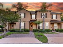 Charming townhome showcasing a brick driveway, tropical landscaping, and two-story facade at 814 Calabria Ave, Davenport, FL 33897