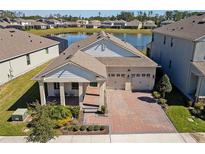 Beautiful exterior view of home with brick driveway, lake view, well-kept lawn, and two-car garage at 8935 Sonoma Coast Dr, Winter Garden, FL 34787
