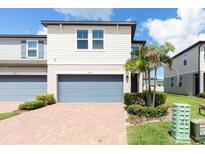 Charming townhouse showcasing a brick driveway and a serene front yard with lush landscaping and a two car garage at 1024 Desert Candle Dr, Ocoee, FL 34761