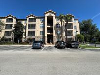 Exterior of a multi-story condo building with palm trees, covered walkways, and parking lot in front at 1370 Tuscan Ter # 2202, Davenport, FL 33896