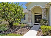Inviting home entrance with stone accents, arched entryway, and well-maintained landscaping at 14128 Bramble Bush Ct, Orlando, FL 32832