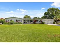 Charming single-story home with a well-manicured lawn, a covered porch, and an attached two car garage at 1505 N Lake Mirror Nw Dr, Winter Haven, FL 33881