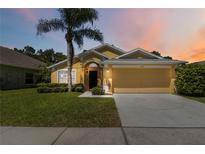 Inviting single-story home features a two-car garage, mature landscaping, and a well-maintained lawn at 165 Scrub Jay Way, Davenport, FL 33896