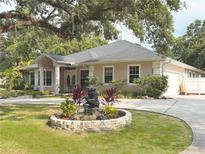 Stunning single-story home with mature trees and a circular driveway, plus a stone water feature at 3100 Pine Needle Trl, Kissimmee, FL 34746