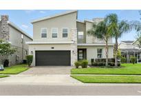 Charming two-story home featuring stone accents, a two-car garage, and a well-manicured lawn with palm trees at 369 Ocean Course Ave, Davenport, FL 33896