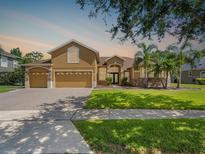 Charming two-story home with manicured lawn, mature trees, and three-car garage on a sunny day at 4951 Parkview Dr, St Cloud, FL 34771