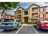 A modern apartment building exterior with balconies, parking, and colorful paint on a partly cloudy day at 6029 Westgate Dr # 726, Orlando, FL 32835