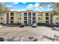 Exterior shot of a yellow apartment building featuring balconies, a parking lot, and blue skies at 1275 Lake Shadow Cir # 13106, Maitland, FL 32751
