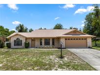 Charming single-story home with brick facade, attached two-car garage, and landscaped front yard on a sunny day at 1299 Buccaneer Ave, Deltona, FL 32725