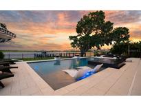 Beautiful pool featuring lounge chairs partially submerged in shallow water and view of the lake at sunset at 15787 Tangerine Dream Ct, Winter Garden, FL 34787