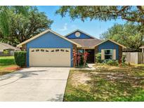 Charming single Gathering home with a beautiful blue exterior, mature trees, and a well maintained lawn at 171 Cedarpark Ln, Davenport, FL 33837