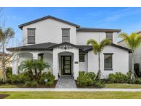 Stunning two-story home with a well-manicured lawn, mature landscaping, and a striking black-and-white design at 7454 Gathering Dr, Reunion, FL 34747