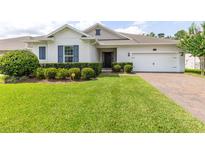 Charming single-story home with lush green lawn, manicured shrubs, and a brick driveway leading to the attached garage at 977 Talon Pl, Winter Springs, FL 32708