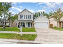 Charming two-story home featuring stone accents, a covered porch, and a well-maintained lawn at 1033 Mccully Ct, Oviedo, FL 32765