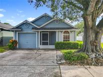 Charming blue single-Gathering home featuring a one-car garage and a well-manicured front yard with mature trees at 1751 Chatham Cir, Apopka, FL 32703