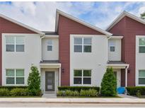 Inviting exterior of townhome featuring red accents, manicured landscaping, and large windows at 193 E Warren Ave, Longwood, FL 32750