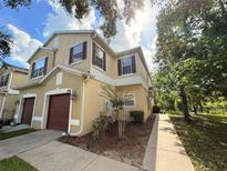 Charming townhome with a one car garage, yellow paint and dark brown shutters in a quiet neighborhood at 1941 Sunset Palm Dr, Apopka, FL 32712