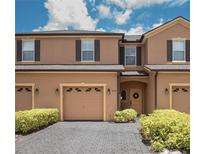 Charming townhome featuring a two-car garage, shuttered windows, and a welcoming entrance with tasteful landscaping at 2241 Retreat View Cir, Sanford, FL 32771