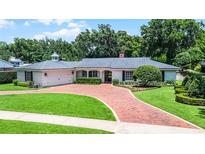 Charming single-story home with a brick driveway, attached garage, manicured lawn, and lush landscaping at 2527 Shrewsbury Rd, Orlando, FL 32803