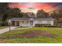 Charming single-story home featuring a well-maintained front yard, covered carport, and inviting entryway during sunset at 7330 Canal Dr, Sanford, FL 32771