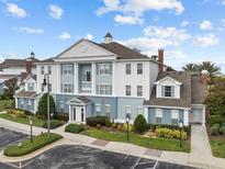 Attractive condo building exterior with blue and white facade, landscaping, and parking area at 7615 Heritage Crossing Way # 201, Reunion, FL 34747