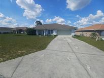 Charming single-story home with a well-maintained lawn and a long driveway leading to a two-car garage at 8509 Sw 136Th Loop, Ocala, FL 34473
