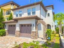 Charming two-story home featuring a two-car garage, stone accents, arched entry, and lush landscaping at 16210 Ravenna Ct, Montverde, FL 34756