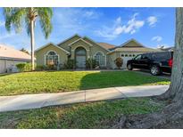 Inviting home exterior featuring a well-manicured lawn, mature trees, and charming architectural details at 1956 Southern Dunes Blvd, Haines City, FL 33844