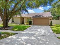 Charming single-story home with a well-manicured lawn and a two-car garage, shaded by a mature tree at 3618 Pompano Ct, Gotha, FL 34734