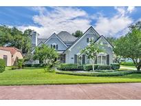 Charming two-story home featuring a landscaped yard, gray stucco, and beautiful architectural details at 413 Harbour Oaks Pointe Dr, Edgewood, FL 32809
