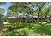 Charming brick home featuring a lush, green lawn and mature trees providing ample shade at 473 Burnt Tree Ln, Apopka, FL 32712