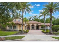 Stunning Mediterranean-style home featuring a red tile roof, arched entryways, and lush landscaping with palm trees at 5413 Via Veneto Ct, Sanford, FL 32771