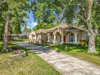 Stunning exterior view of the home with stucco, grand columns and mature trees at 5489 Glen Oak Place, Sanford, FL 32771