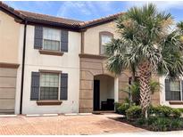 Charming two-story townhome with a red brick driveway and lush tropical landscaping at 8806 Geneve Ct, Kissimmee, FL 34747