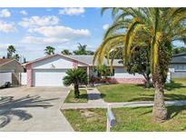 Charming single-story home with a lush front yard, white exterior with pink accents, and a two-car garage at 109 Woodfield Ct, Sanford, FL 32773
