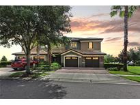 Beautiful two-story home with a well-manicured lawn, mature trees, and brick paved driveway at 1269 Long Cove Loop # 1269, Davenport, FL 33896