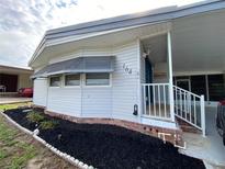 Charming home exterior featuring meticulous landscaping, a covered porch, and vinyl siding at 164 Royal Palm Dr, Leesburg, FL 34748