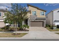 Modern two-story home with stone accents, a two-car garage, and manicured landscaping at 1811 Caribbean View Ter, Kissimmee, FL 34747