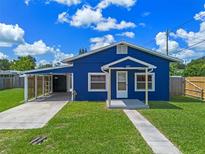 Charming blue home featuring a well-manicured lawn, carport, and inviting front porch at 205 9Th St, St Cloud, FL 34769