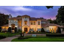 Elegant two-story home showcasing meticulous landscaping, iron gate, and distinctive Mediterranean-style architecture at 2211 Azalea Pl, Winter Park, FL 32789
