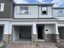 Two-story townhome with stone accents, light gray siding, an open garage and front door at 5087 Prairie Preserve Run, St Cloud, FL 34772