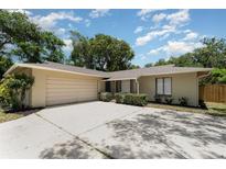 Charming single-story home featuring a large driveway and an attached garage, surrounded by mature trees and lush landscaping at 917 Great Bend Rd, Altamonte Springs, FL 32714