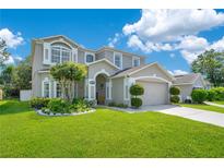 Beautiful two-story home with a well-manicured lawn, mature landscaping, and neutral color palette at 9846 Palmetto Dunes Ct, Orlando, FL 32832