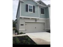 Charming two-story home with a light-colored exterior, a garage, and dark window shutters at 12337 Turtle Grass Dr, Orlando, FL 32824