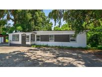 Charming single-story home with white and black exterior paint, surrounded by mature trees at 1257 N Pine Hills Rd, Orlando, FL 32808
