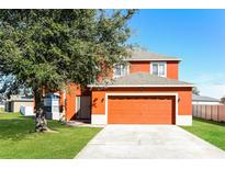 Two-story home with an attached garage, lush green lawn, and mature tree in front at 148 Conch Dr, Kissimmee, FL 34759