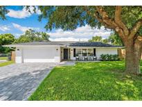 Charming single-story home featuring a brick driveway, a lush green lawn, and rocking chairs on the front porch at 2114 Geigel Ct, Orlando, FL 32806